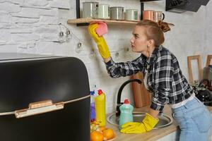 mujer en guantes limpieza mueble con trapo a hogar cocina. foto