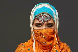 Studio shot of a chrming female wearing the colorful hijab decorated with sequins and jewelry. Arabic style. photo