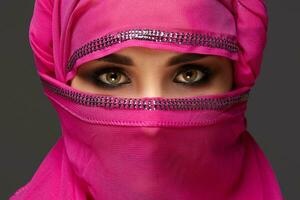 Close-up shot of a young charming woman wearing the pink hijab decorated with sequins. Arabic style. photo