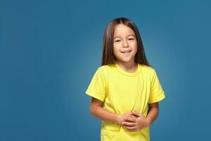 pequeño niña en amarillo camiseta es sonriente foto