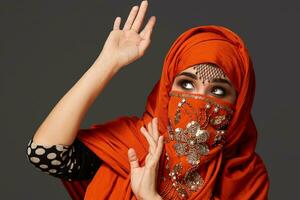 Studio shot of a young charming woman wearing the terracotta hijab decorated with sequins and jewelry. Arabic style. photo