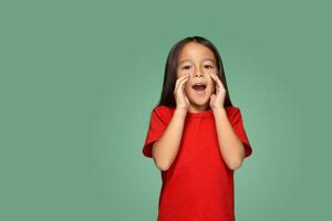 Portrait of a small pretty girl standing sideways and calling someone holding her hand near her mouth photo