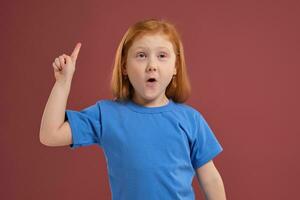 Portrait of cute redhead emotional little girl on red background photo