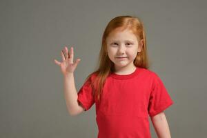 A little girl shows gesture - five fingers, isolated on grey background photo