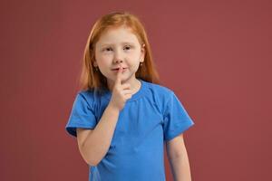 Portrait of cute redhead emotional little girl on red background photo