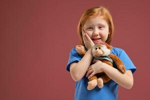 Portrait of cute redhead emotional little girl on red background photo