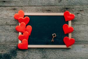 pizarra y corazones con un llave en un de madera antecedentes. San Valentín día concepto. Copiar espacio. foto
