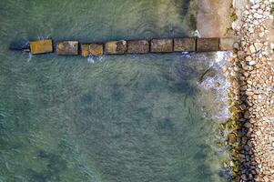 Aerial top view from drone to the seacoast and old concrete pier, summer sea background. photo