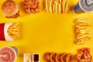 Top view hamburger, french fries and fried chicken on yellow background. Copy space for your text. photo