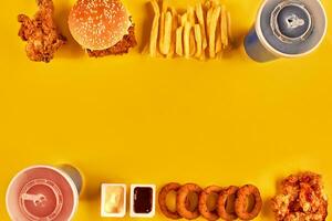 Top view hamburger, french fries and fried chicken on yellow background. Copy space for your text. photo