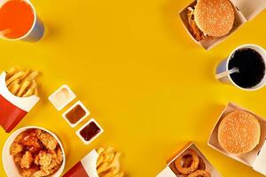 Fast food dish top view. Meat burger, potato chips and wedges. Take away composition. French fries, hamburger, mayonnaise and ketchup sauces on yellow background. photo