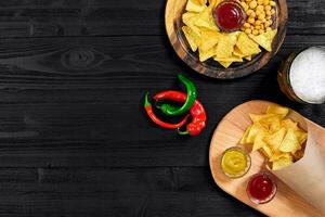 Lager beer and snacks on black wooden table. Nuts, chips. Top view with copyspace photo