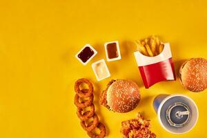 Top view hamburger, french fries and fried chicken on yellow background. Copy space for your text. photo