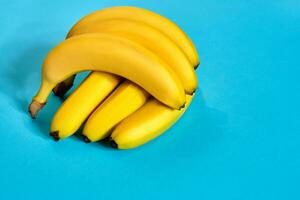 Fresh bananas close up on bright blue background. Flat lay. Summer concept. photo