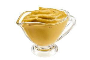 Mustard sauce in a glass sauceboat isolated on white background with copy space for text or images. Spices and herbs. Close-up shot. photo