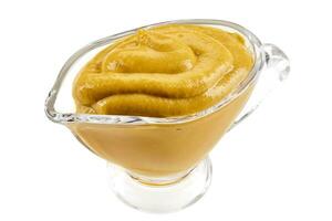 Mustard sauce in a glass sauceboat isolated on white background with copy space for text or images. Spices and herbs. Close-up shot. photo
