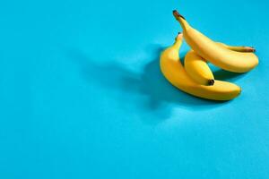 Fresh bananas close up on bright blue background. Flat lay. Summer concept. photo