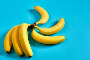 Yellow ripe bananas on blue background with space for text or design. Top view photo