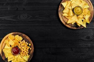 Overhead view of snacks with sauce on black wooden table. photo