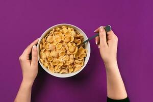 Food, healthy eating, people and diet concept - close up of woman eating muesli for breakfast over purple background photo