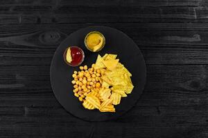 Overhead view of snacks with sauce on black wooden table. photo