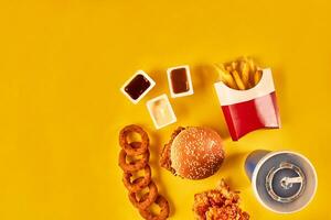 Top view hamburger, french fries and fried chicken on yellow background. Copy space for your text. photo