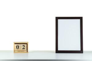 Wooden calendar 02 January with frame for photo on white table and background