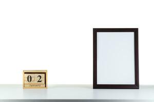Wooden calendar 02 January with frame for photo on white table and background