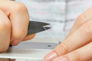 Female hands of a master tailor cuts a thread with scissors photo