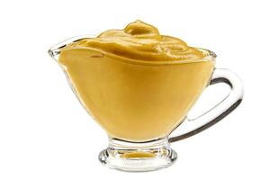 Mustard sauce in a glass sauceboat isolated on white background with copy space for text or images. Spices and herbs. Close-up shot. photo
