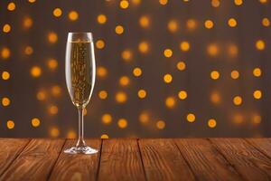 Glasses with champagne on a wooden background against a bokeh background of lights photo