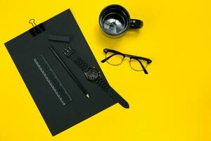 Black objects from the office on a yellow background. Work and creativity. Top view. photo