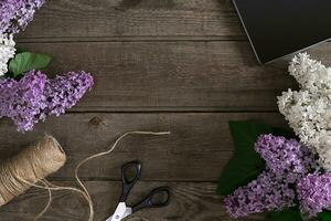 Lilac blossom on rustic wooden background with empty space for greeting message. Top view photo