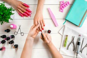 Nail care. Closeup of female hands filing nails with professional nail file in beauty nail salon. Top view photo