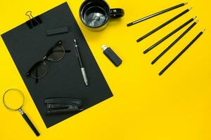 Black objects from the office on a yellow background. Work and creativity. Top view. photo