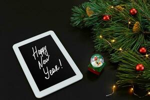 Table with tablet computer, christmas toys, stars and fluffy fir branches. Free space for text. Top view. photo