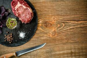 Dry aged raw beef steak with ingredients for grilling photo