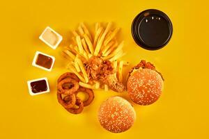 Fast food concept with greasy fried restaurant take out as onion rings, burger, fried chicken and french fries as a symbol of diet temptation resulting in unhealthy nutrition. photo