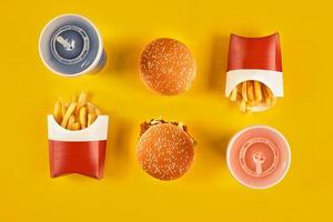 Fast food and unhealthy eating concept - close up of fast food snacks and cold drink on yellow background photo