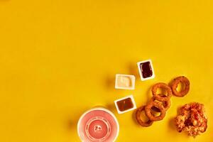 Fast food and unhealthy eating concept - close up of fast food snacks and cold drink on yellow background photo