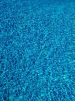 Blue water ripple in swimming pool with sun reflections photo