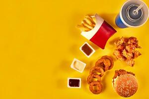 Top view hamburger, french fries and fried chicken on yellow background. Copy space for your text. photo