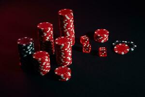 Dice and red and black chips on dark background photo
