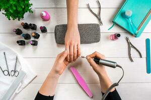 Manicure for the client. Close-up of the hands of a manicurist and client on a wooden background photo