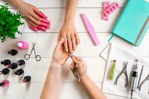 manicura para el cliente. de cerca de el manos de un manicuro y cliente en un de madera antecedentes foto