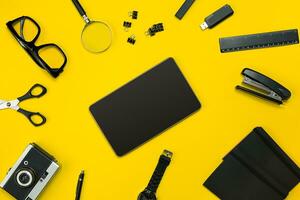 Black objects from the office on a yellow background. Work and creativity. Top view. photo