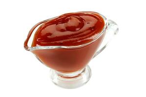 Ketchup sauce in a glass sauceboat isolated on white background with copy space for text or images. Spices and herbs. Close-up shot. photo