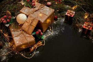 Christmas gifts and garland near green spruce branch on a black background. Christmas background. Top view. photo