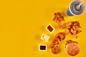 Fast food and unhealthy eating concept - close up of fast food snacks and cold drink on yellow background photo