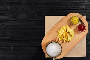 Glass of beer with nachos chips on a wooden background. photo